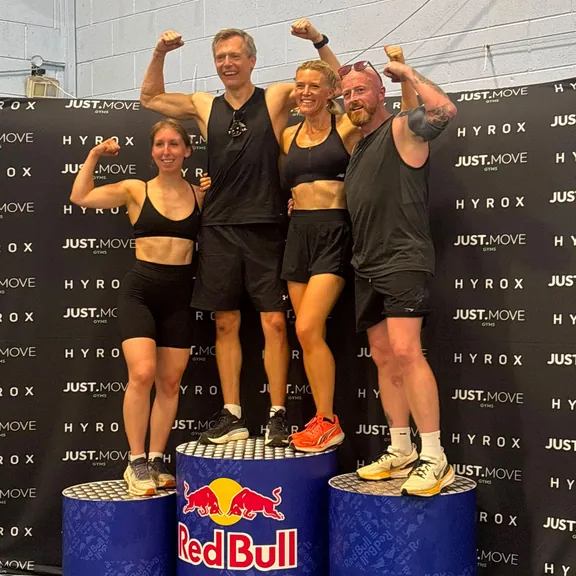 Four athletes flexing on a podium at the Leeds Hyrox simulation event relay, July 2026